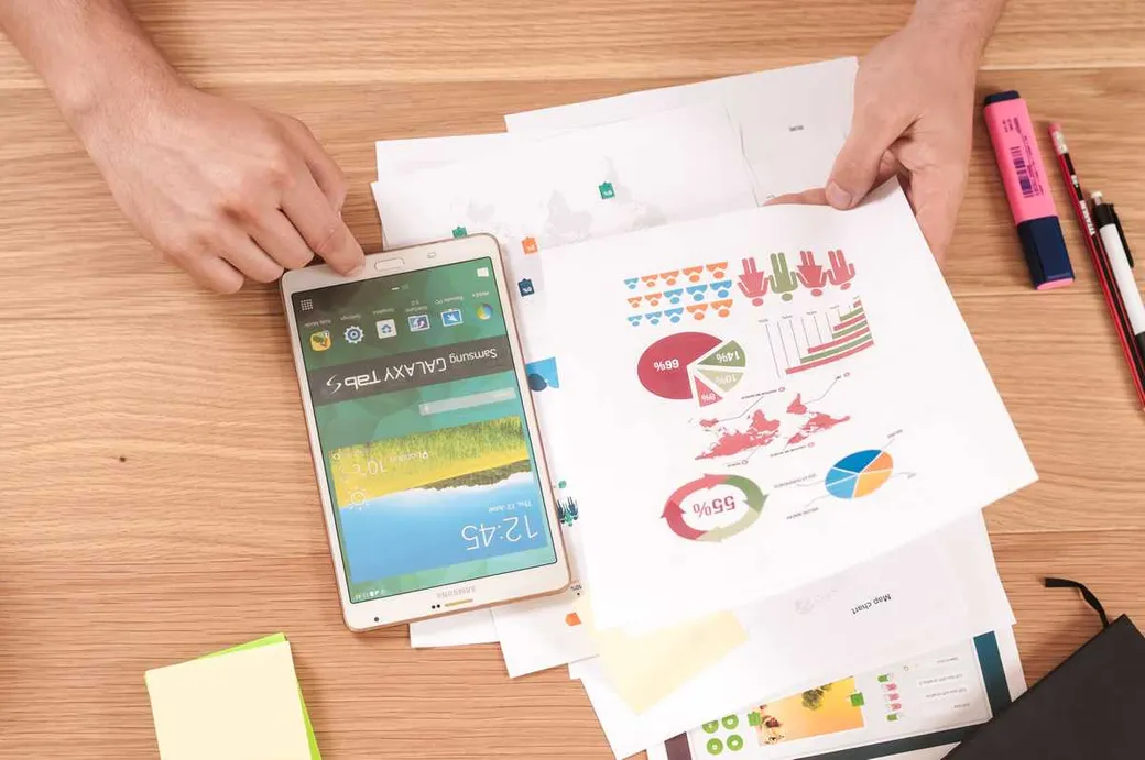 Bureau de travail avec une tablette affichant des graphiques, posée sur des documents d’analyse